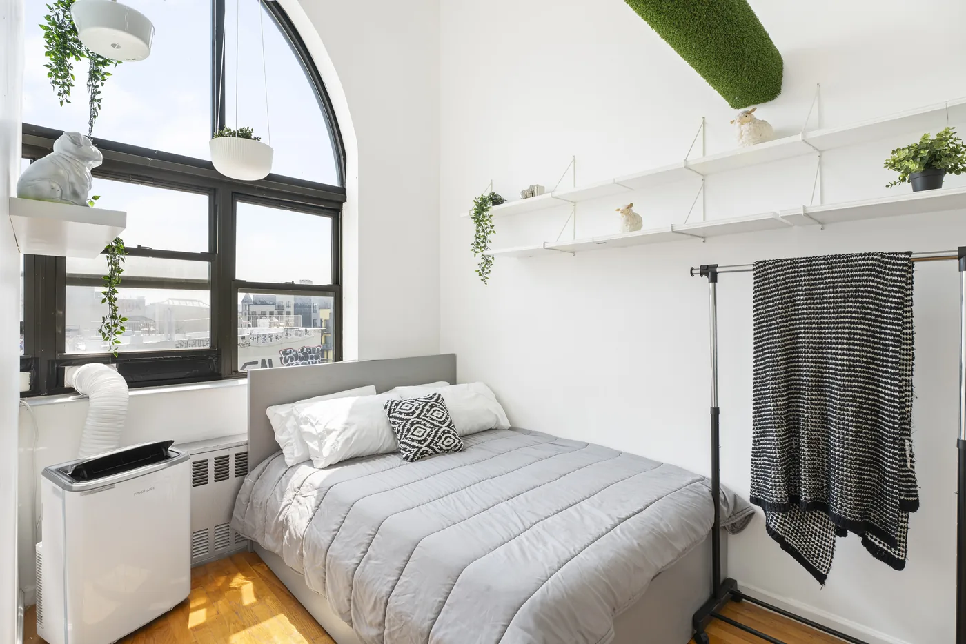 Loft bedroom with arched window and city view photographed for a New York City real estate listing.